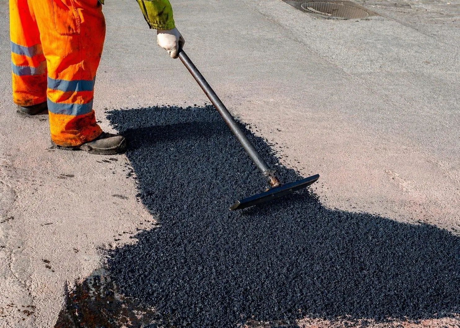Operario realizando bacheo con mezcla asfáltica BACHEX en calle