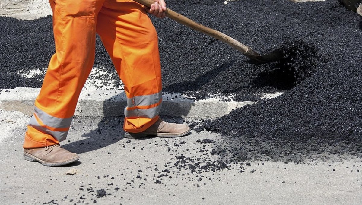 Operario de bacheo trabajando la calzada antes de la demarcación vial, reparación con BACHEX